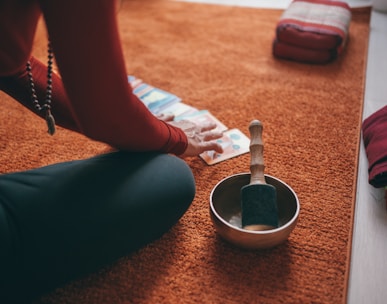 person in teal pants sitting on floor with black round ceramic bowl