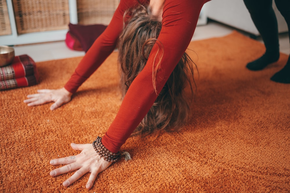 woman in red long sleeve shirt and red pants lying on brown carpet
