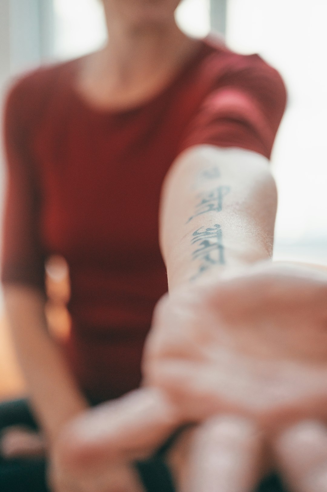 person in red crew neck shirt with tattoo on right foot