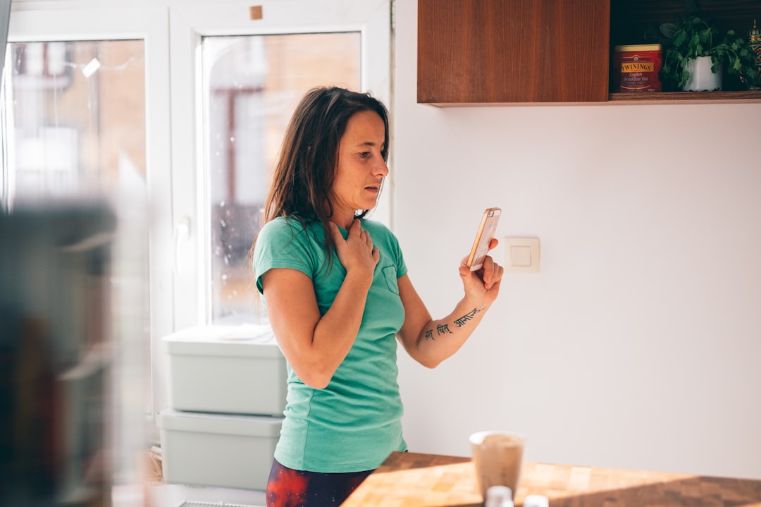 woman in green shirt holding smartphone