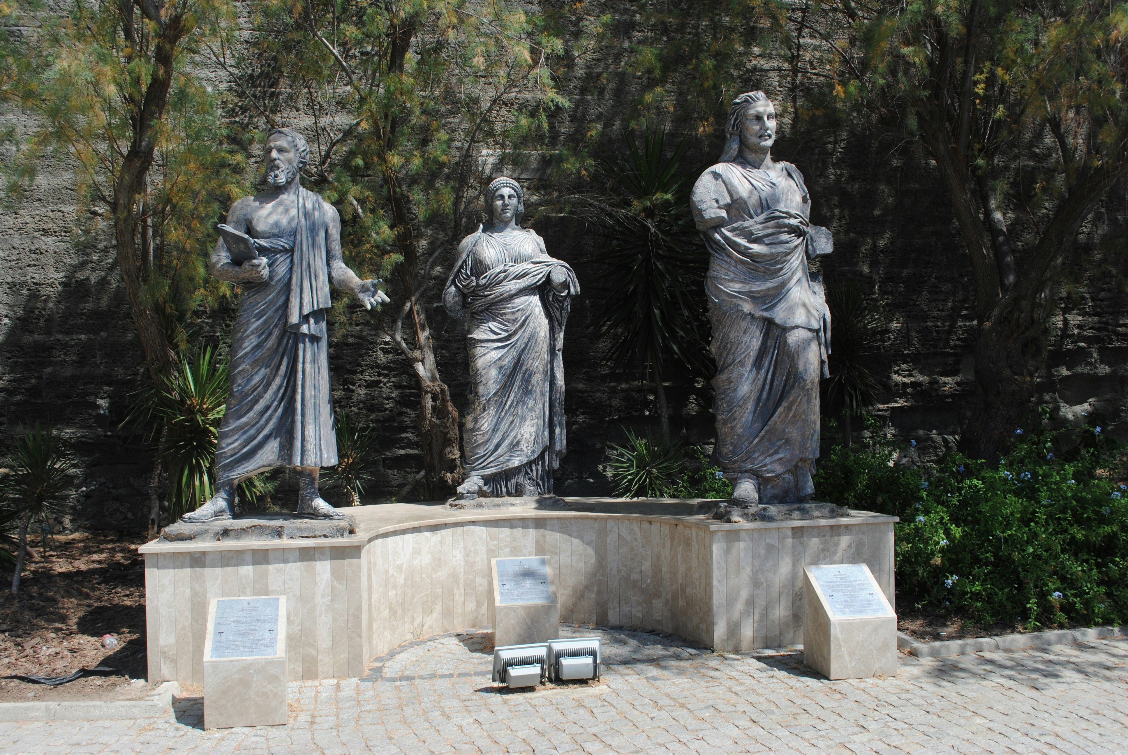 man in robe statue near green trees during daytime
