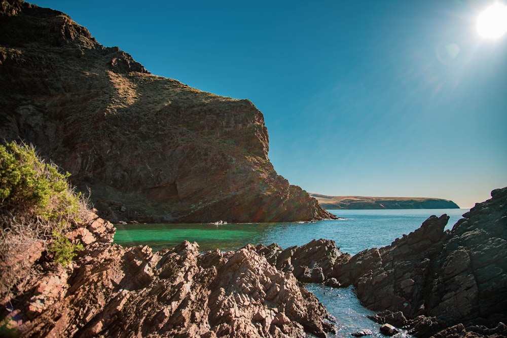 Formación rocosa marrón en el mar bajo el cielo azul durante el día