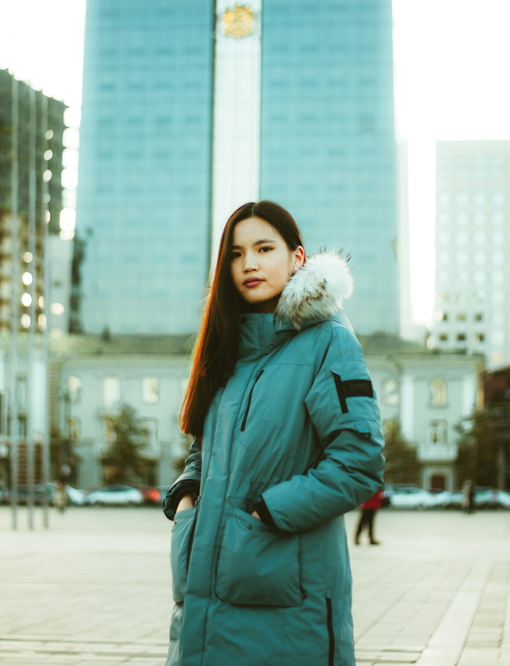 woman in blue jacket standing on road during daytime