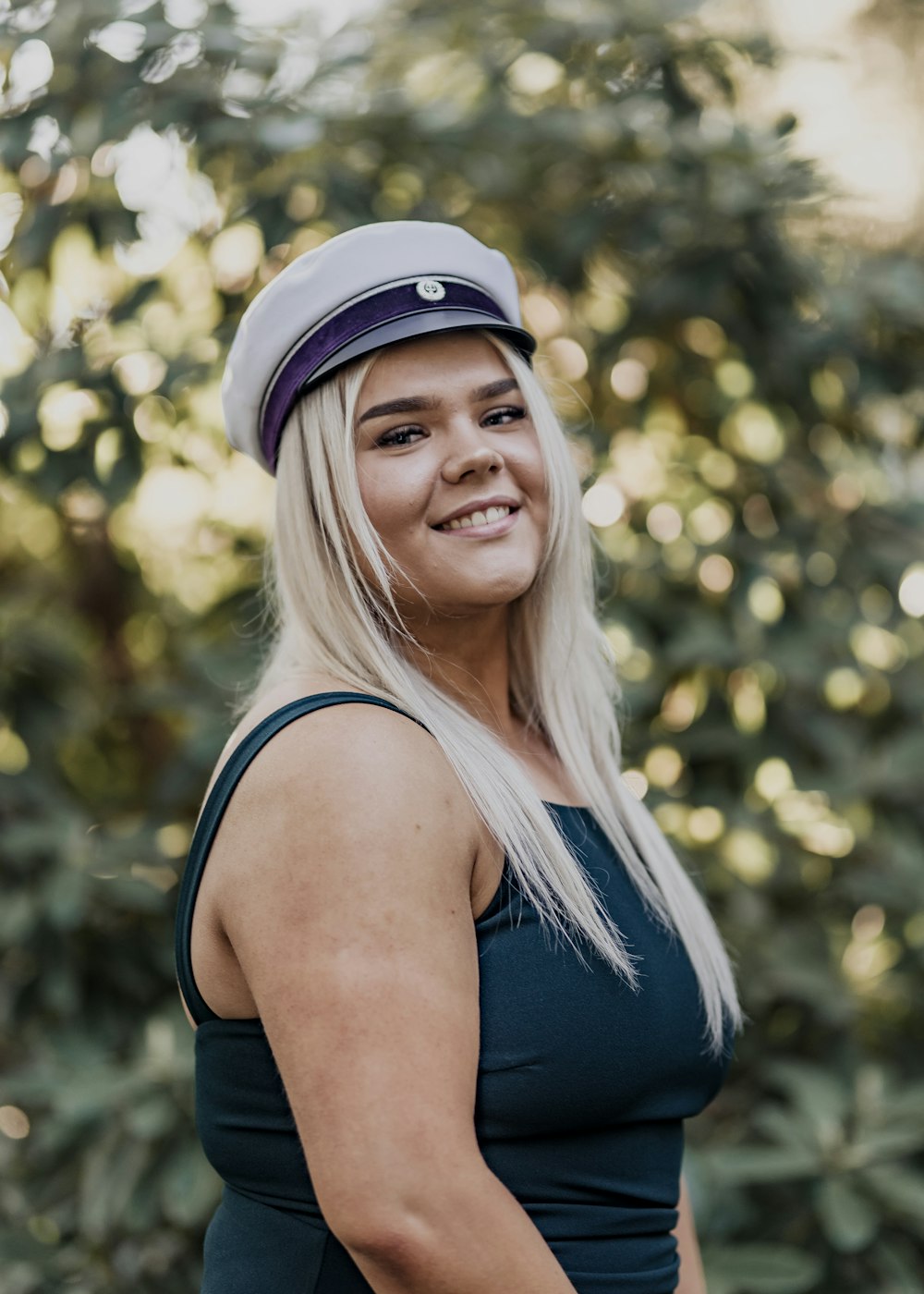 woman in black tank top and white cap smiling