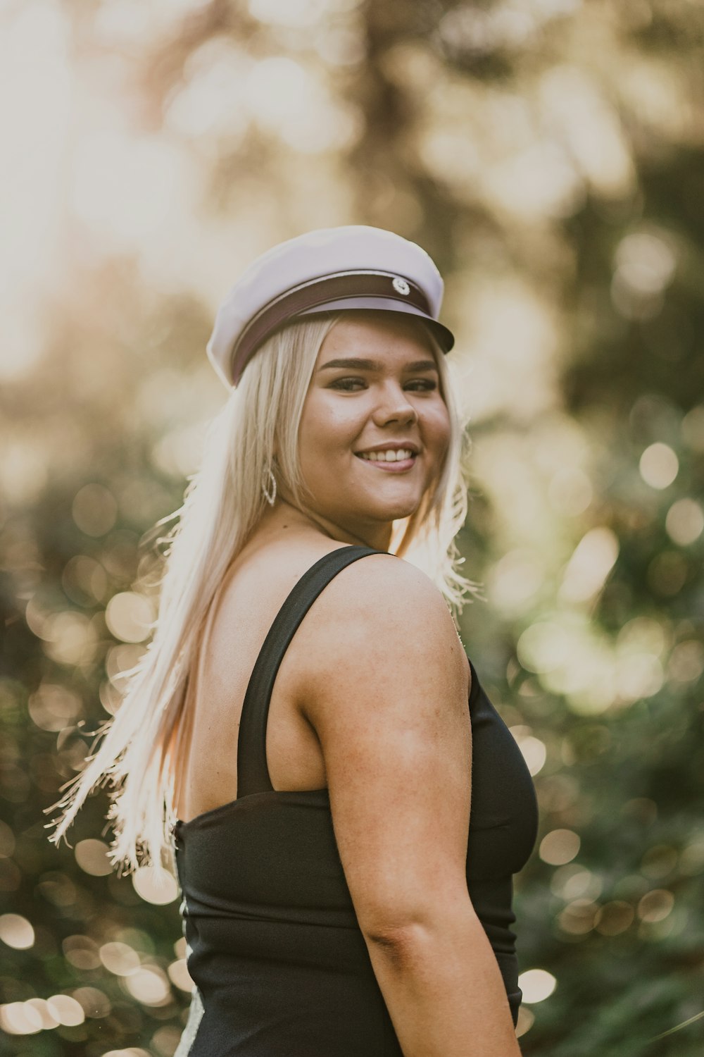 woman in black tank top wearing white cap smiling