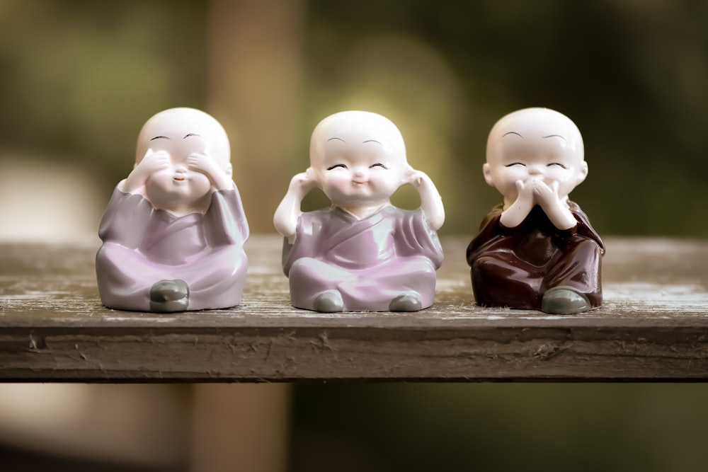 two white ceramic figurines on brown wooden shelf