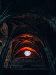 An ancient cathedral interior bathed in warm orange light highlighting stained glass windows.