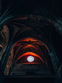 An ancient cathedral interior bathed in warm orange light highlighting stained glass windows.
