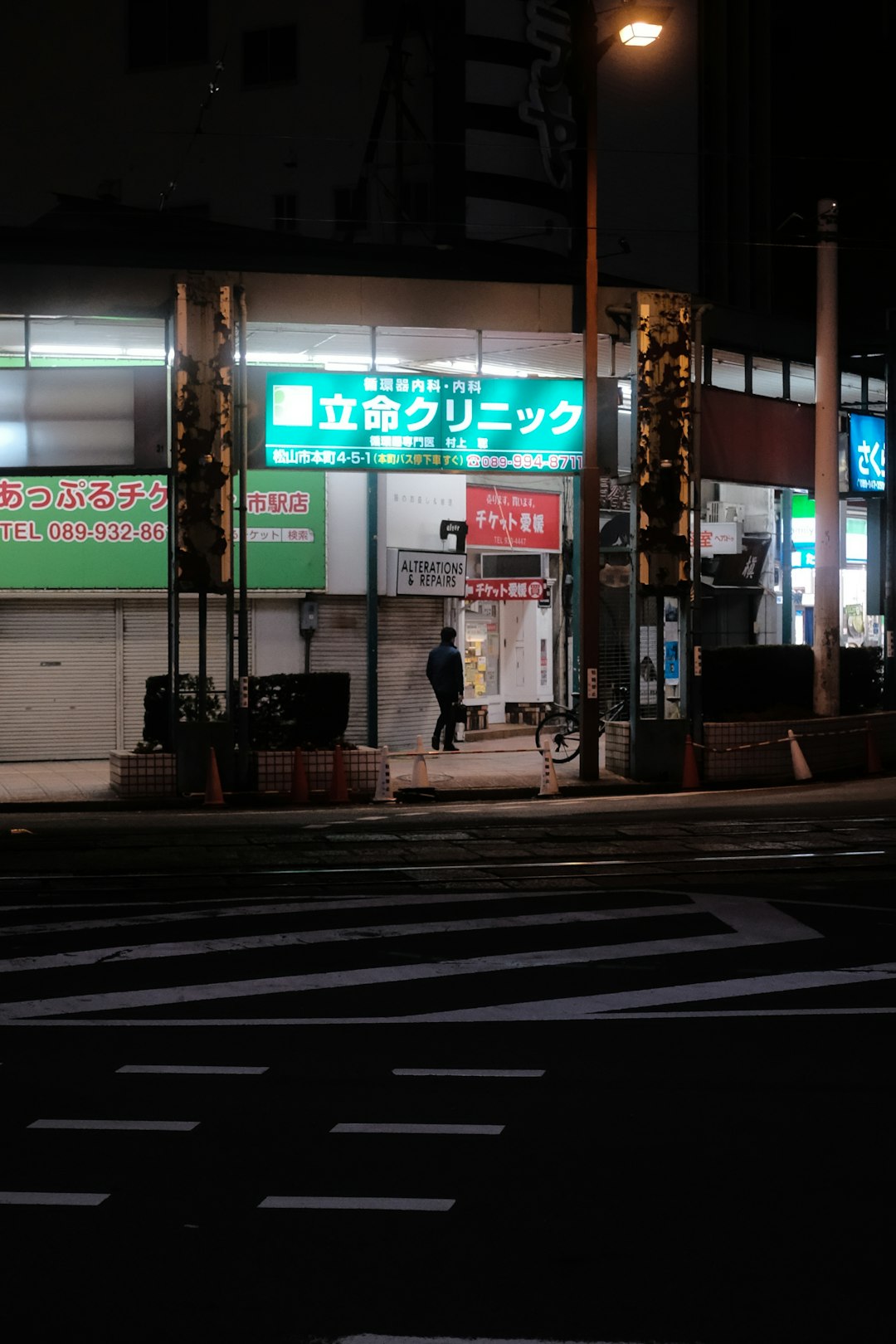 man in black jacket walking on sidewalk during night time