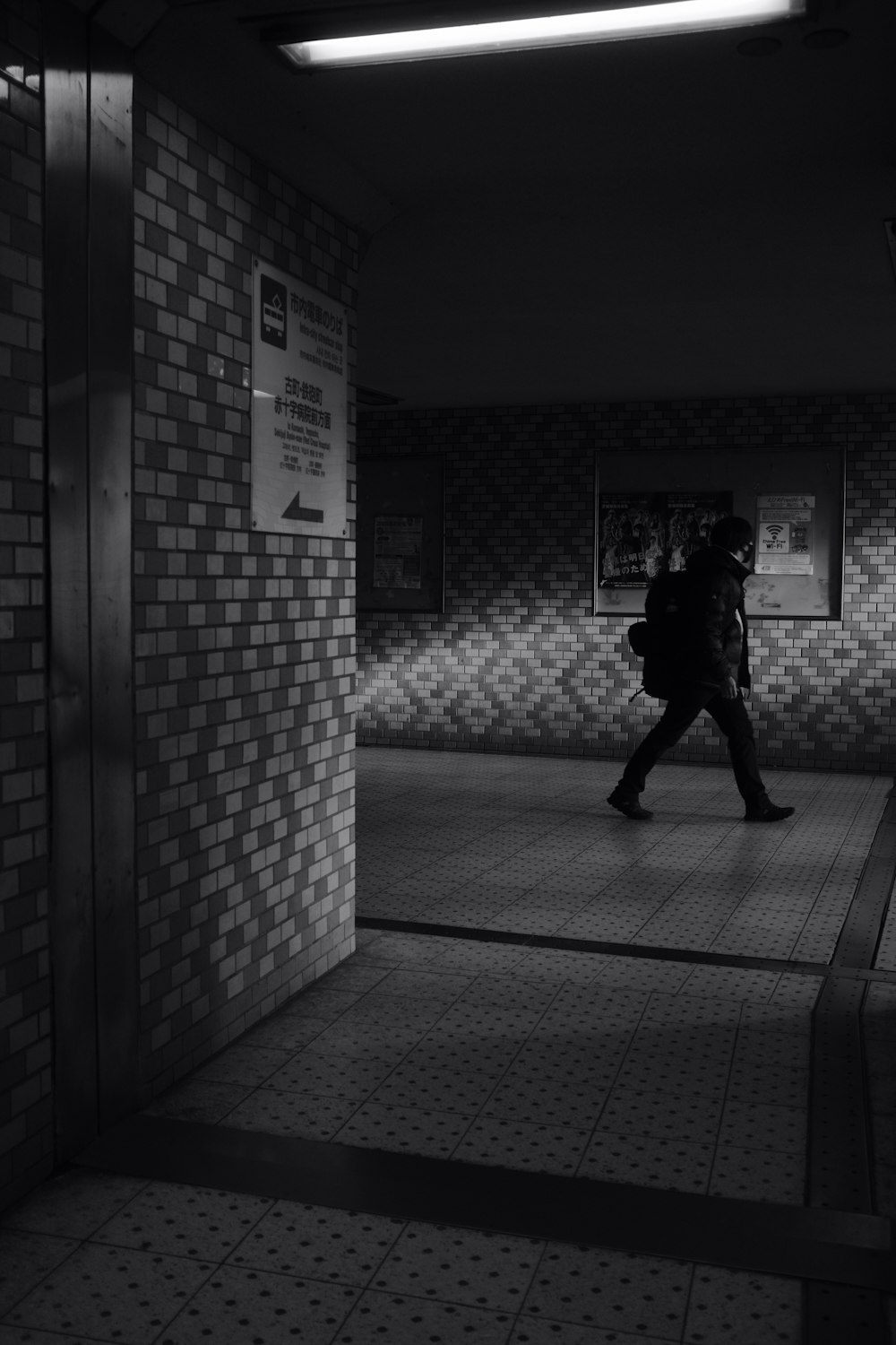 man walking on hallway in grayscale photography