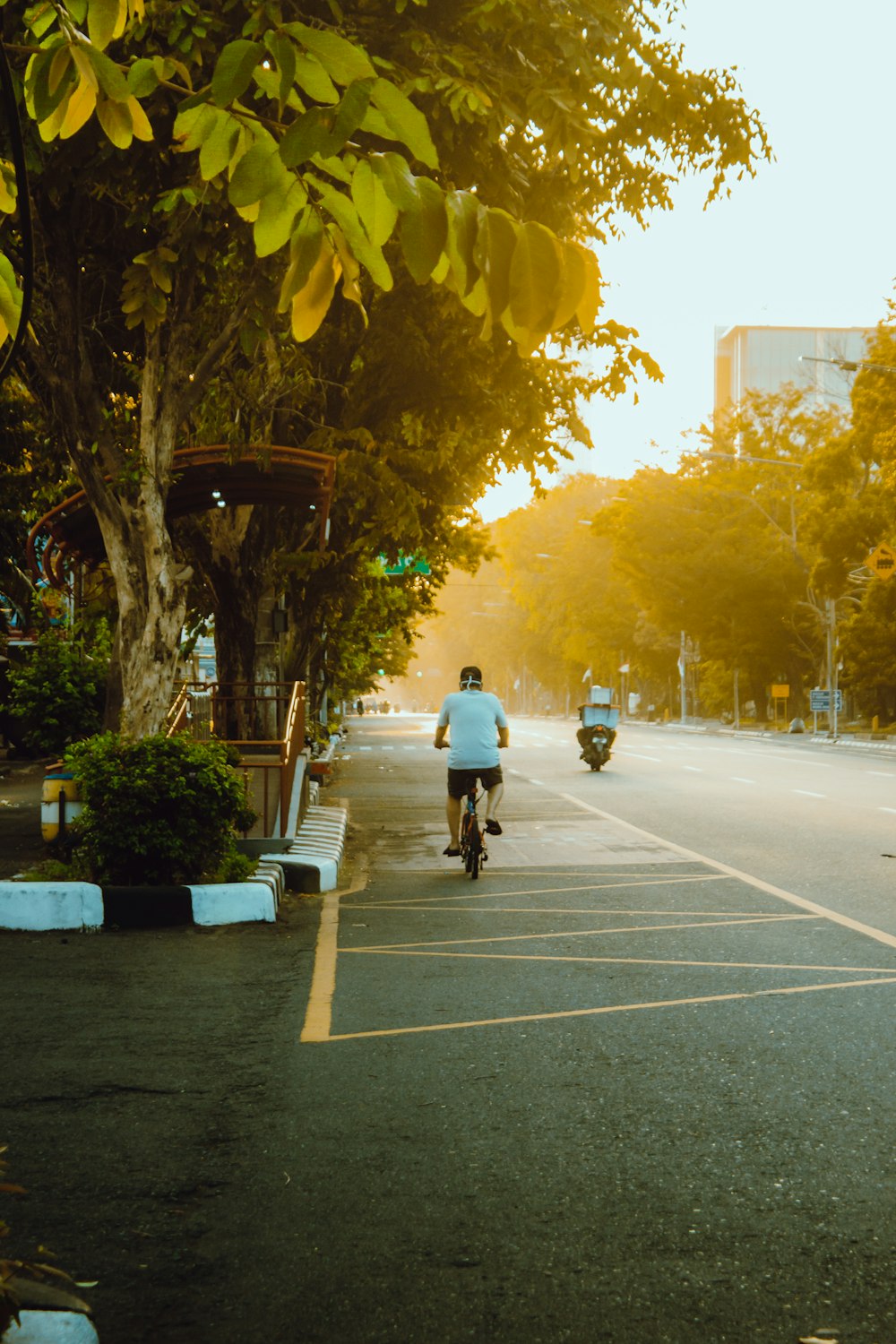 man in white shirt riding bicycle on road during daytime