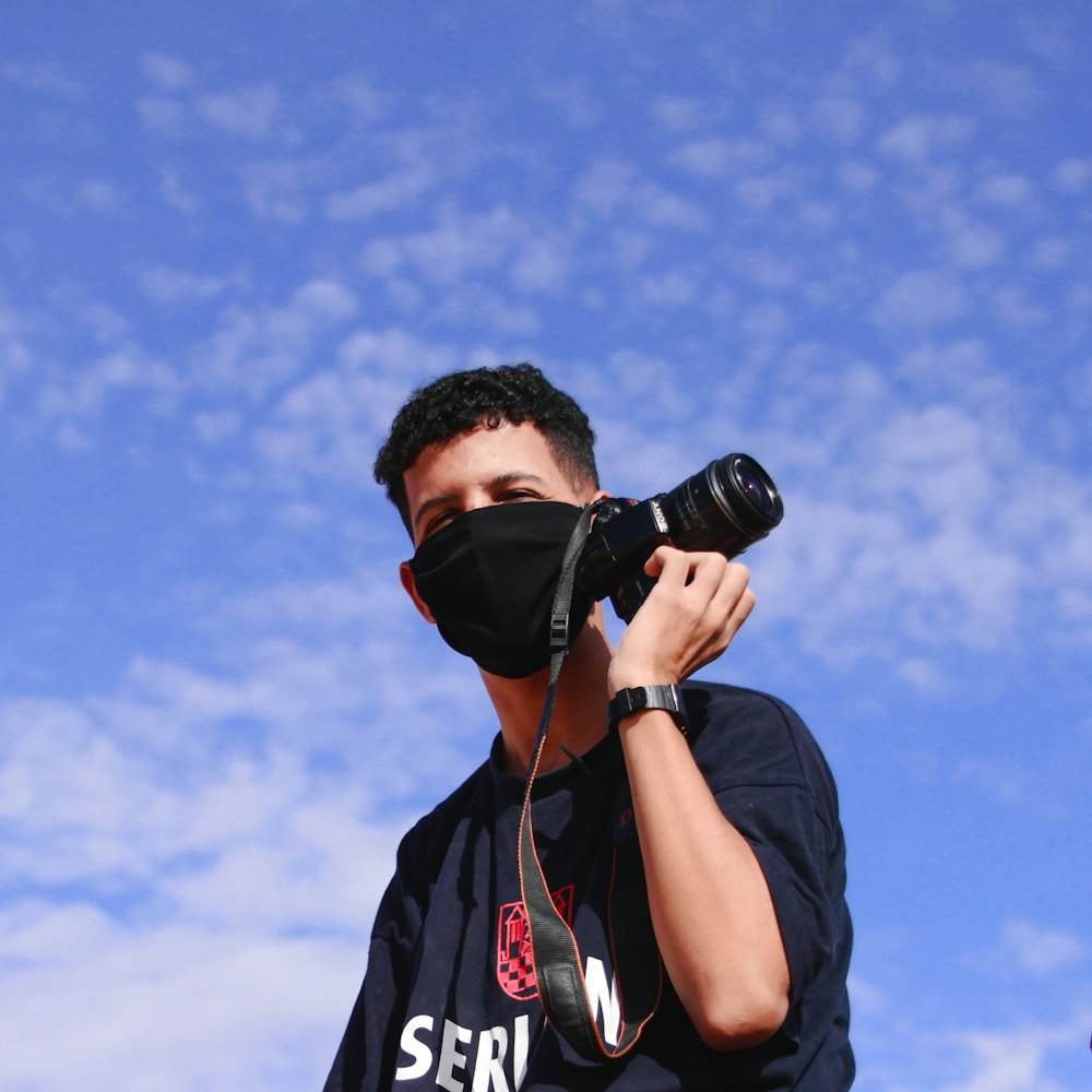 man in black and red crew neck t-shirt using black dslr camera
