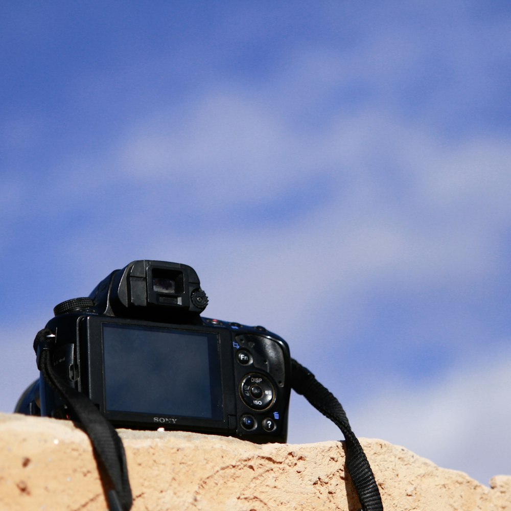 black dslr camera on brown rock