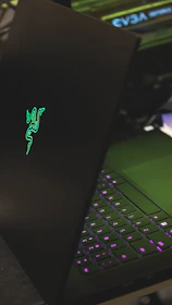 High-end gaming laptop with neon purple lighting on a minimalist gray surface