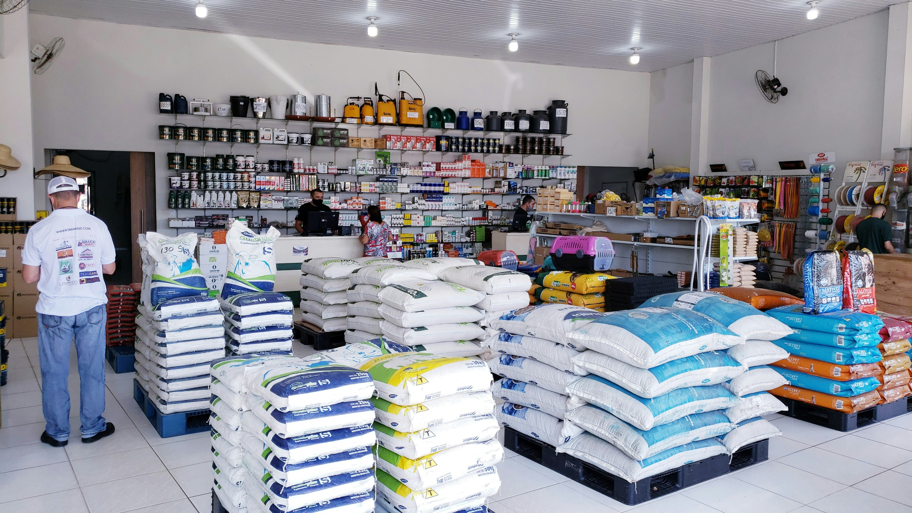 Agro-vet shop owner standing in front of stocked animal feed shelves in Kampala store