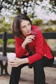 woman in red long sleeve shirt holding white disposable cup