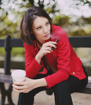 woman in red long sleeve shirt holding white disposable cup