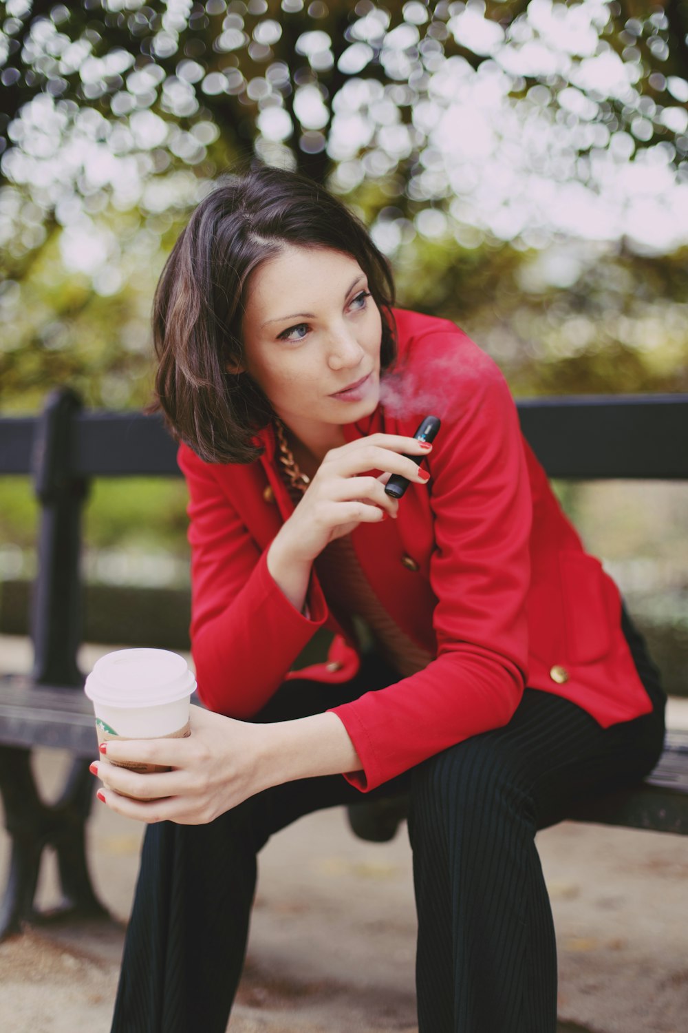 woman in red long sleeve shirt holding white disposable cup