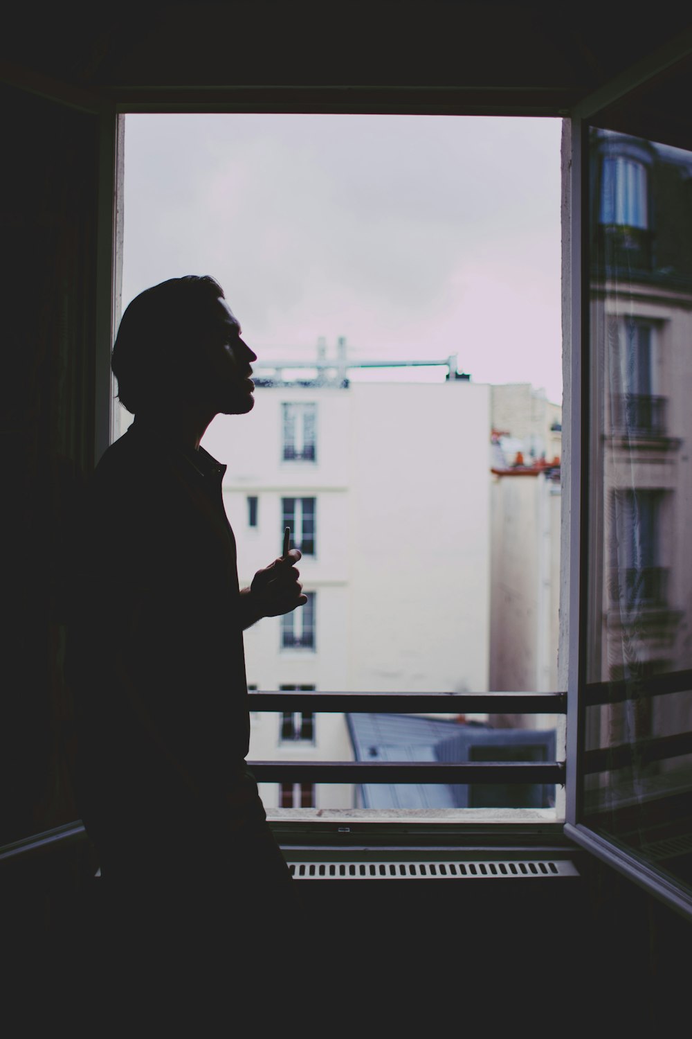 silhouette of man standing near window during daytime