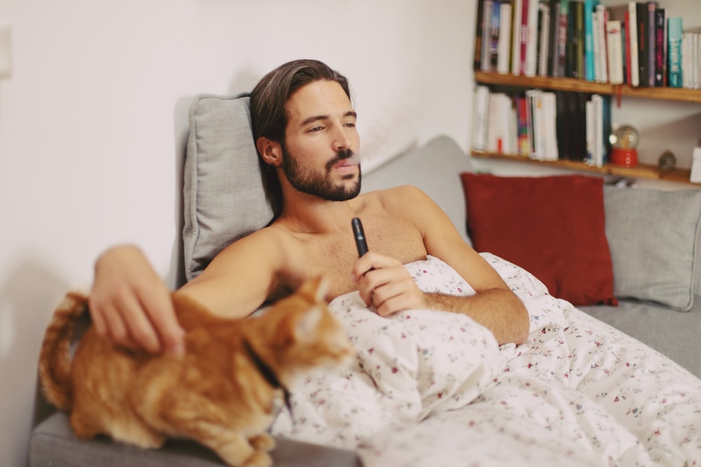 woman in white and black tank top lying on bed with brown dog