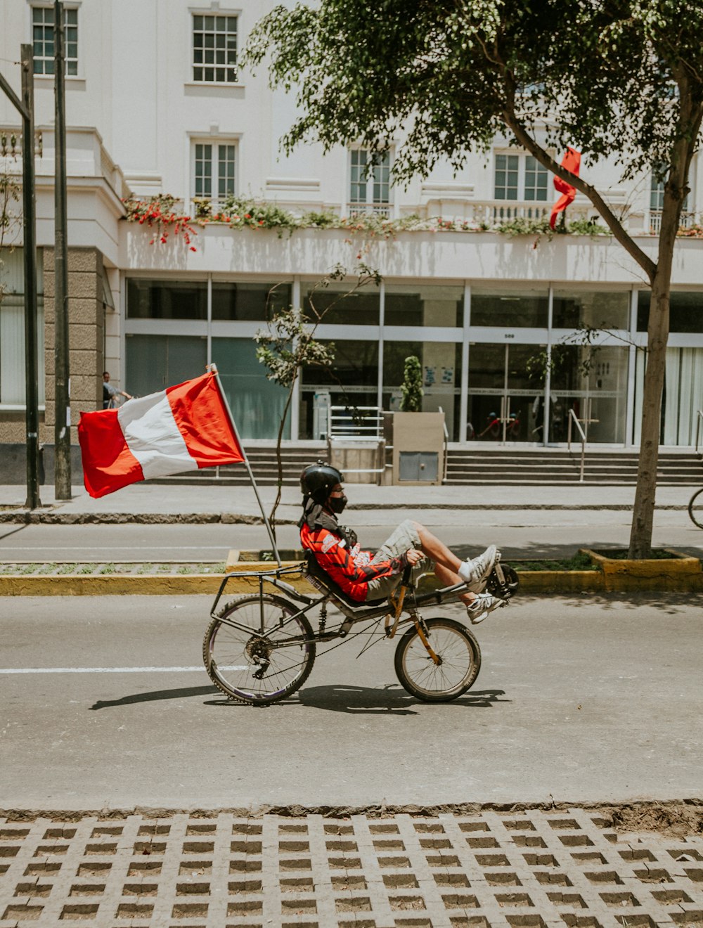 昼間の道路で自転車に乗る赤いシャツの男性