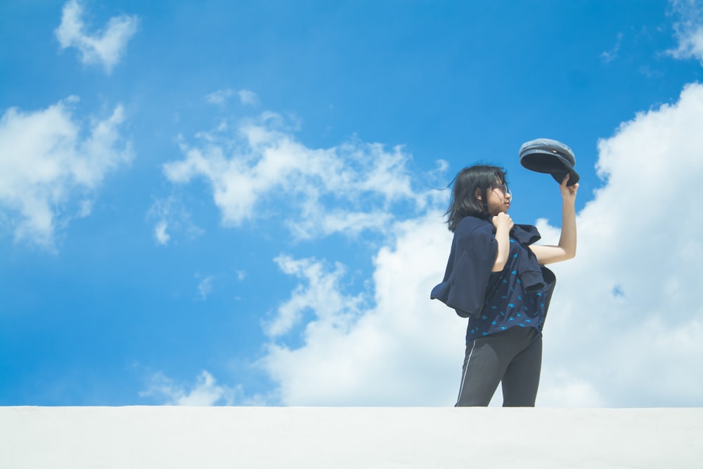 woman in blue denim jacket and blue denim shorts standing under blue sky and white clouds