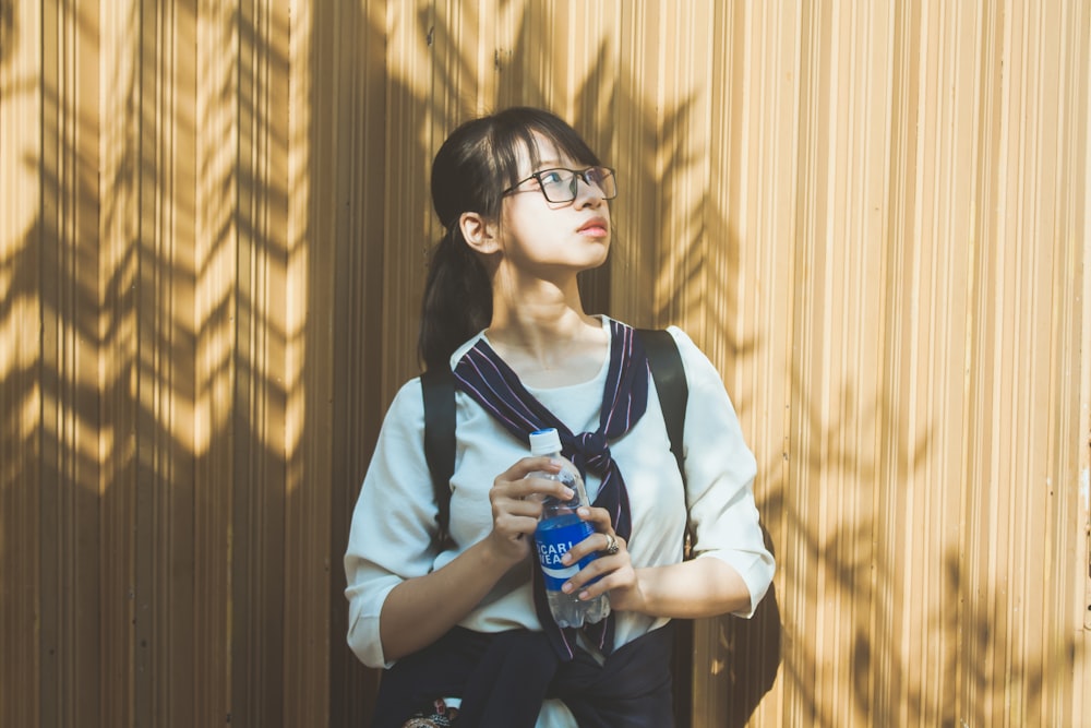 woman in white and black long sleeve shirt holding blue bottle