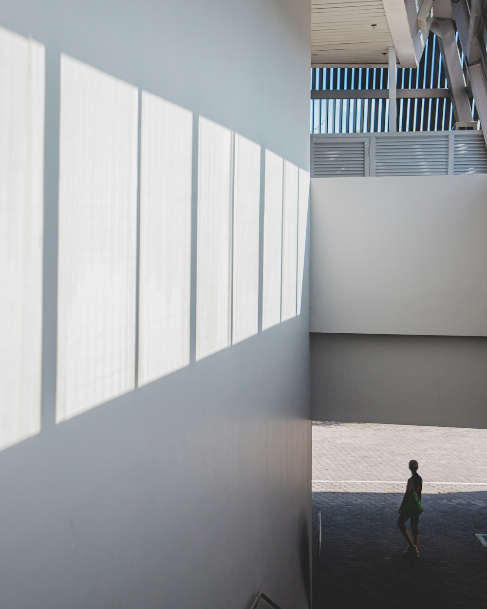 woman in black dress walking on white concrete building