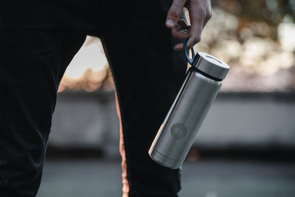 person holding stainless steel travel mug