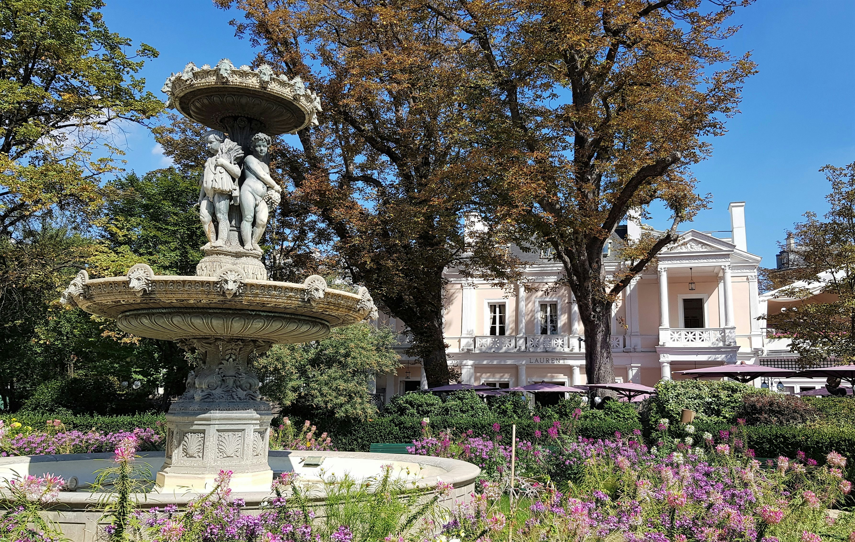 brown concrete fountain in the middle of green grass field, 