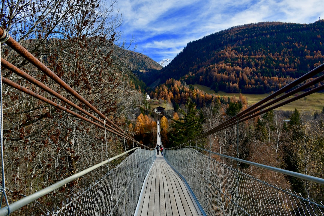 white wooden bridge over green mountains during daytime