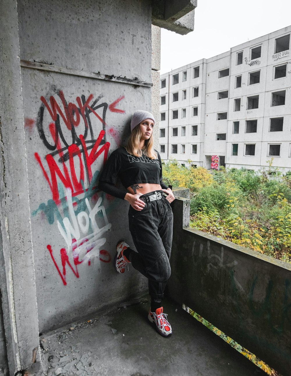 woman in black jacket and black pants sitting on concrete wall