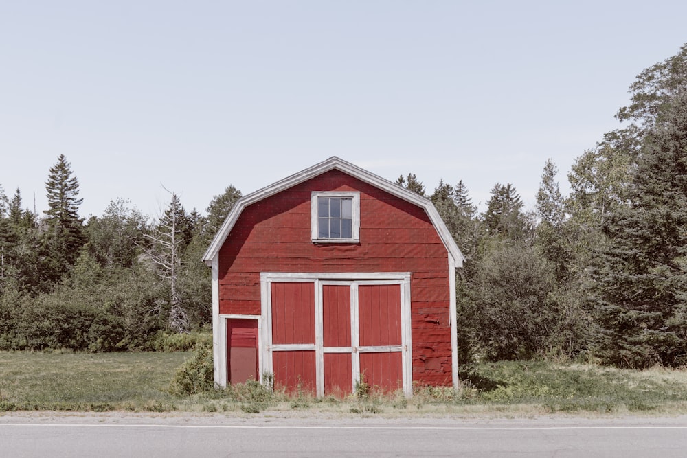 red and white wooden barn house near green trees under white sky during daytime