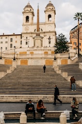man in black jacket sitting on brown concrete stairs during daytime