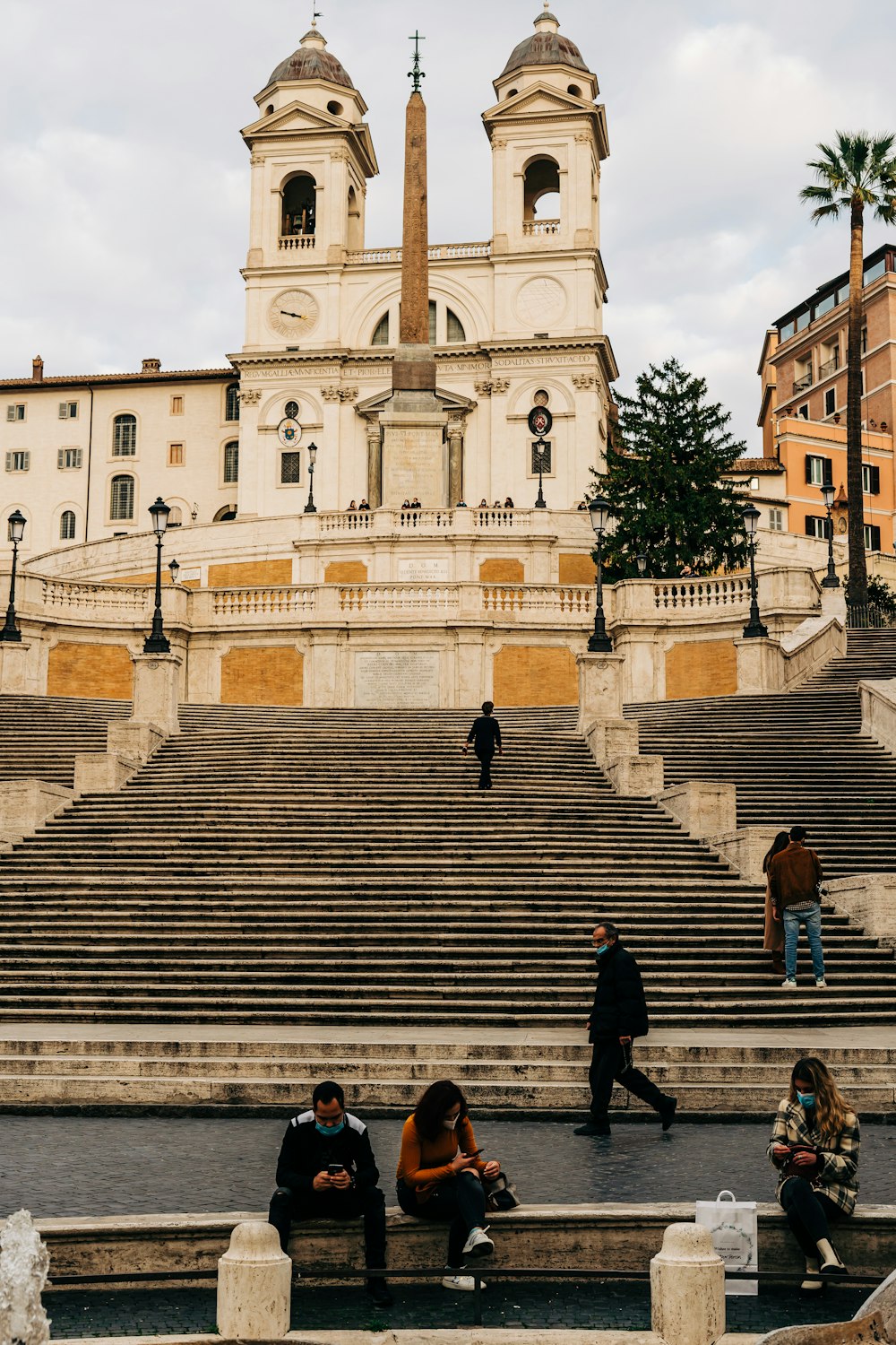 man in black jacket sitting on brown concrete stairs during daytime