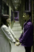 An intimate moment of a couple holding hands against a charcoal-textured wall.