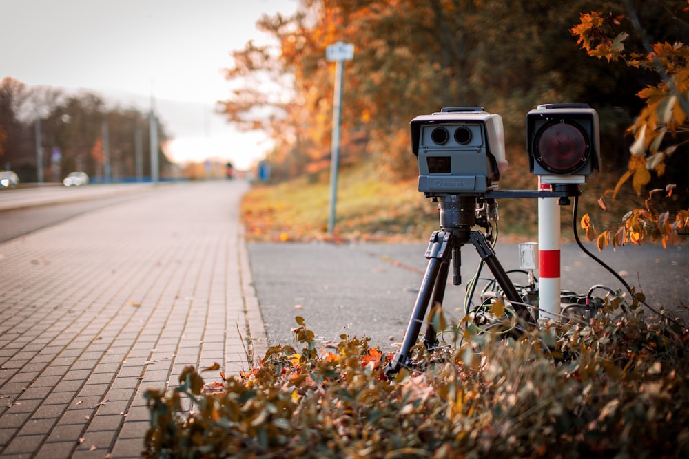 Macchina fotografica nera e grigia sul treppiede sulla strada durante il giorno