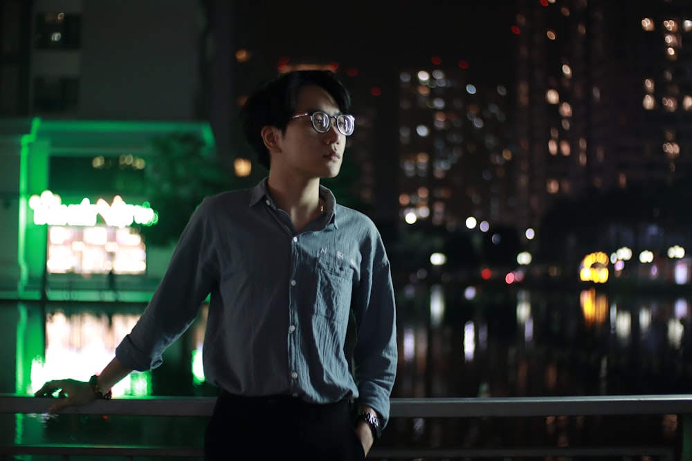 man in blue dress shirt and black pants wearing black sunglasses