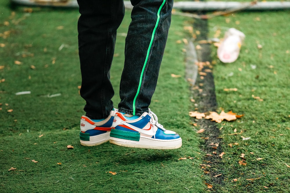 person in black pants wearing blue and white nike sneakers