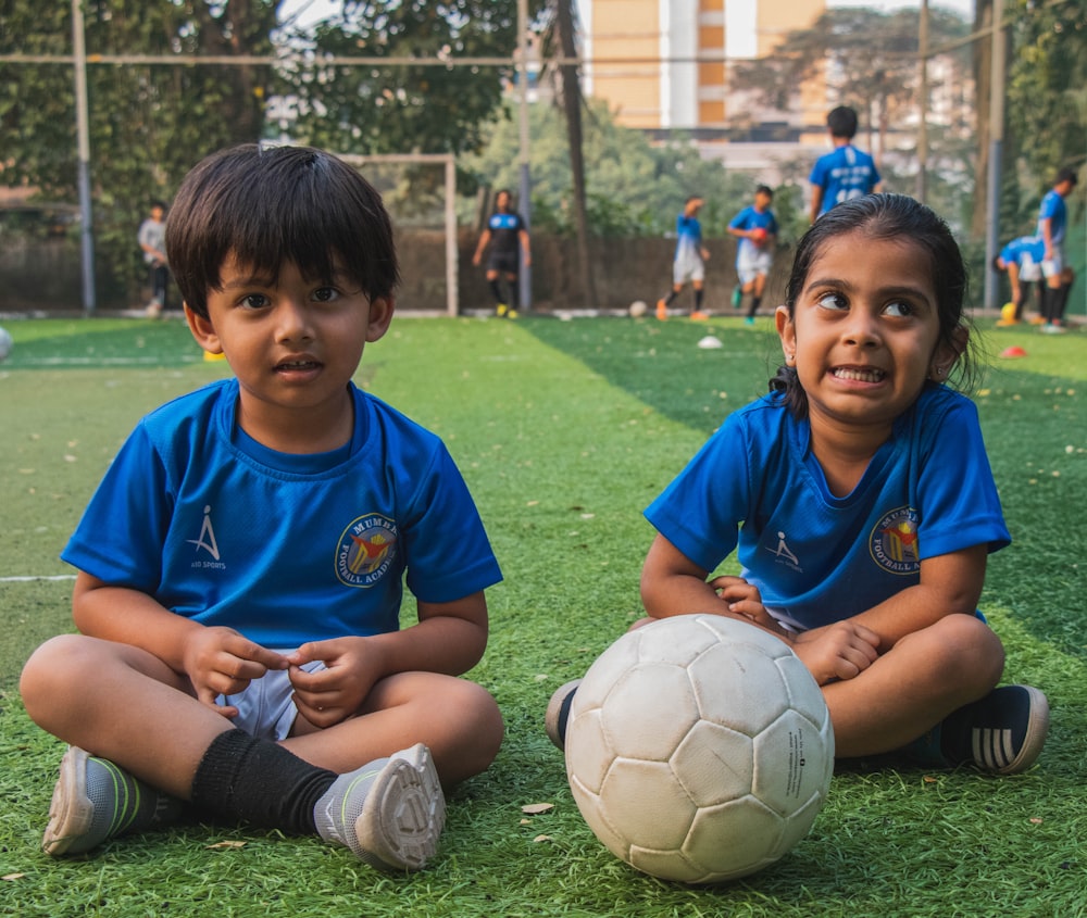 boy in blue polo shirt playing soccer during daytime