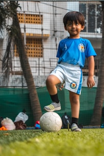 boy in blue soccer jersey shirt and white shorts playing soccer during daytime