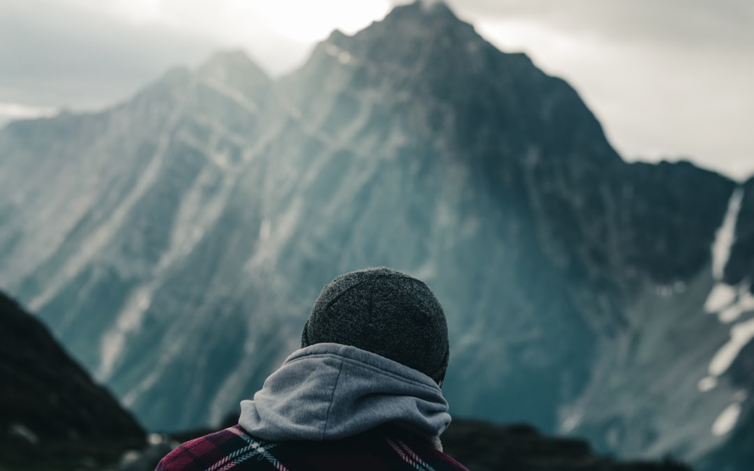 person in black knit cap and gray hoodie looking at the mountains during daytime
