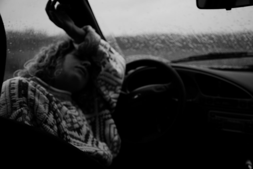 grayscale photo of man driving car