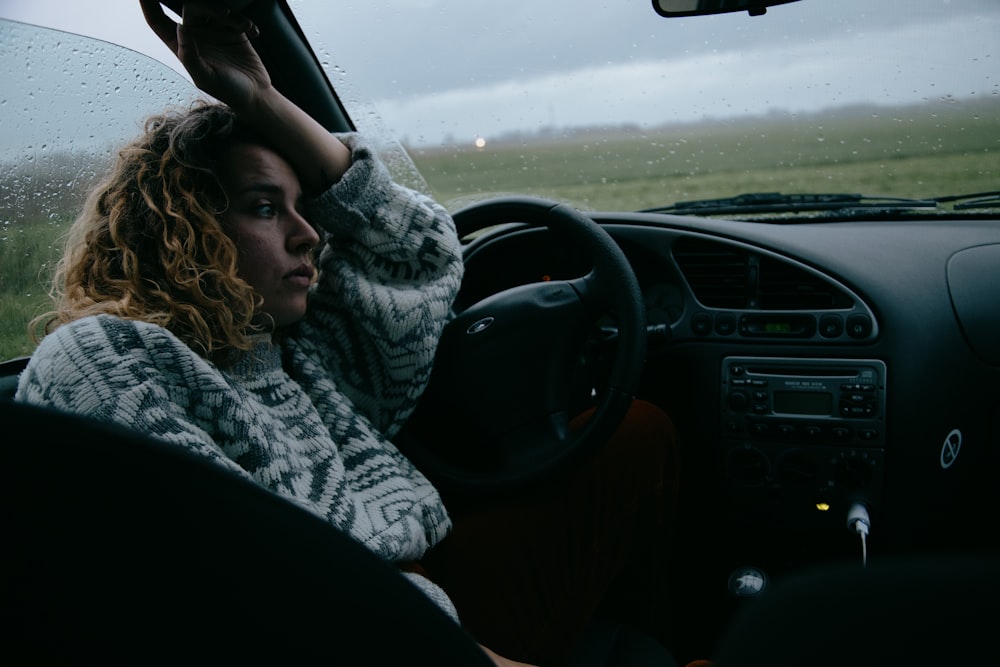 Mujer con bufanda blanca y negra conduciendo coche