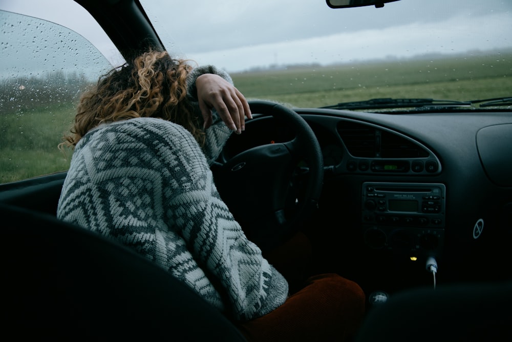 person in gray and white sweater driving car