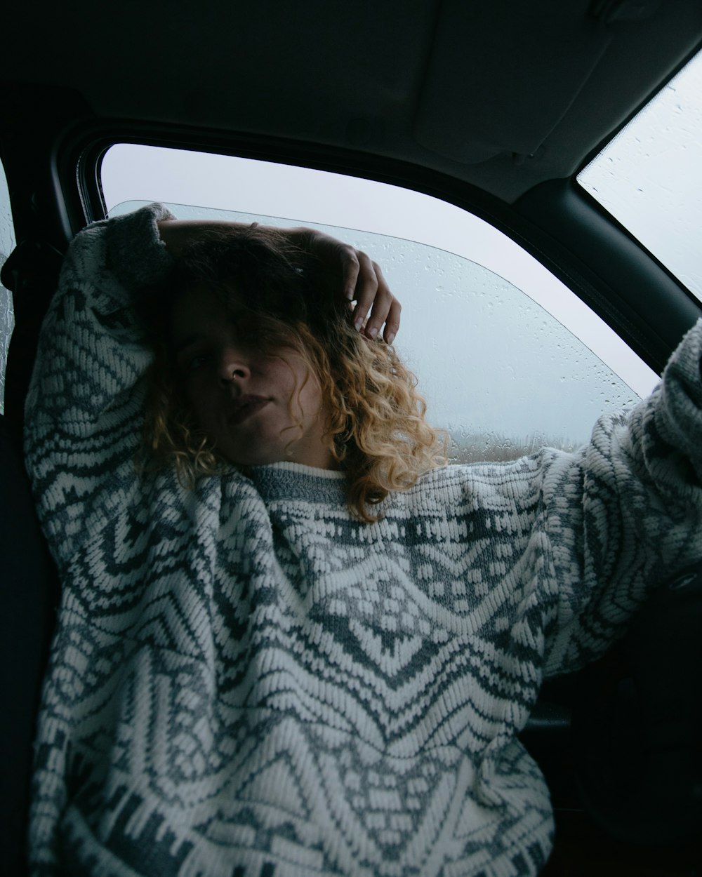 woman in gray and white sweater sitting inside car