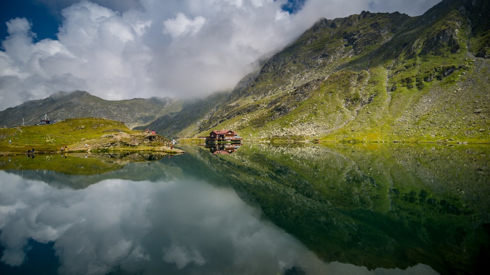 green and brown mountain beside lake under cloudy sky during daytime