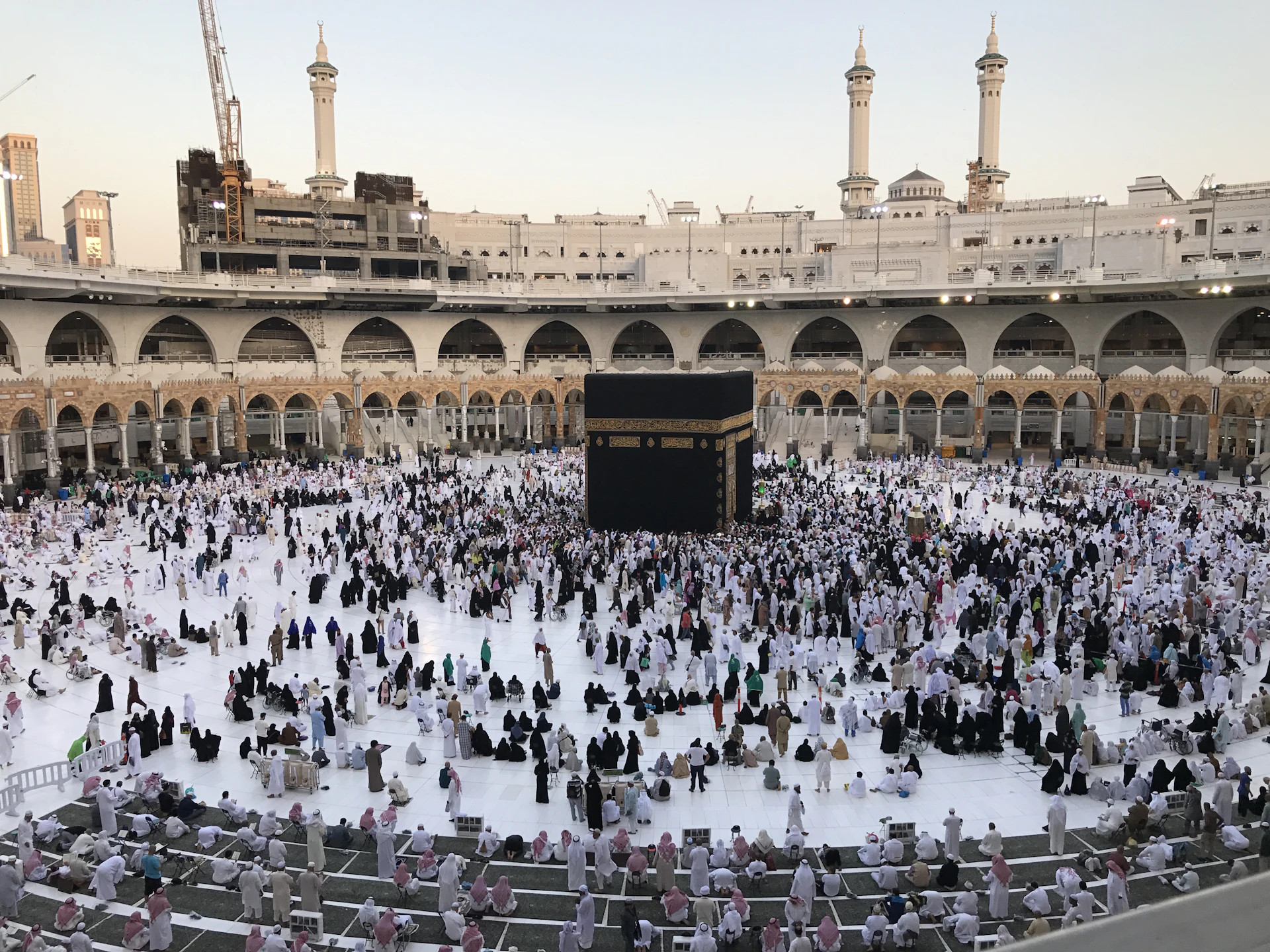 Pilgrims gathered around the Kaaba at Masjid al-Haram in warm morning light