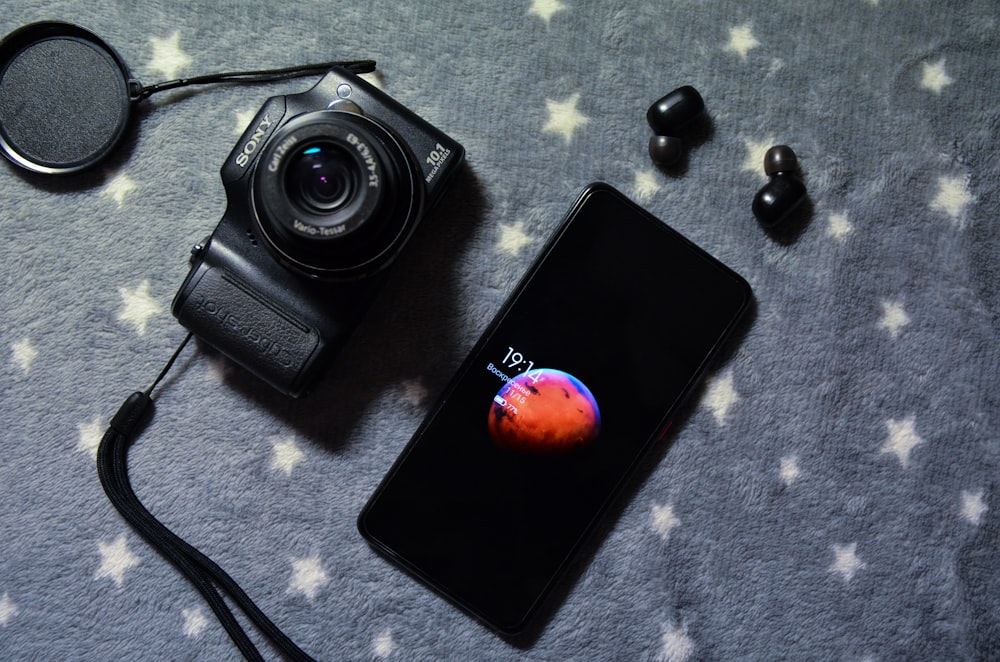 black samsung android smartphone beside black camera