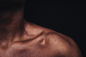 A close-up of a woman's collarbone illuminated by soft, dramatic lighting with velvet textures in the background.